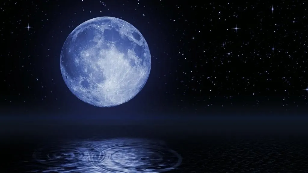 Las 8 fases de la luna explicadas: Guía completa sobre el ciclo lunar, curiosidades y mucho más para aprender cada fase lunar 30 Foto de la luna llena en el horizonte sobre el mar, en tonos azulados, y texto sobreimpreso: La Luna Hoy.